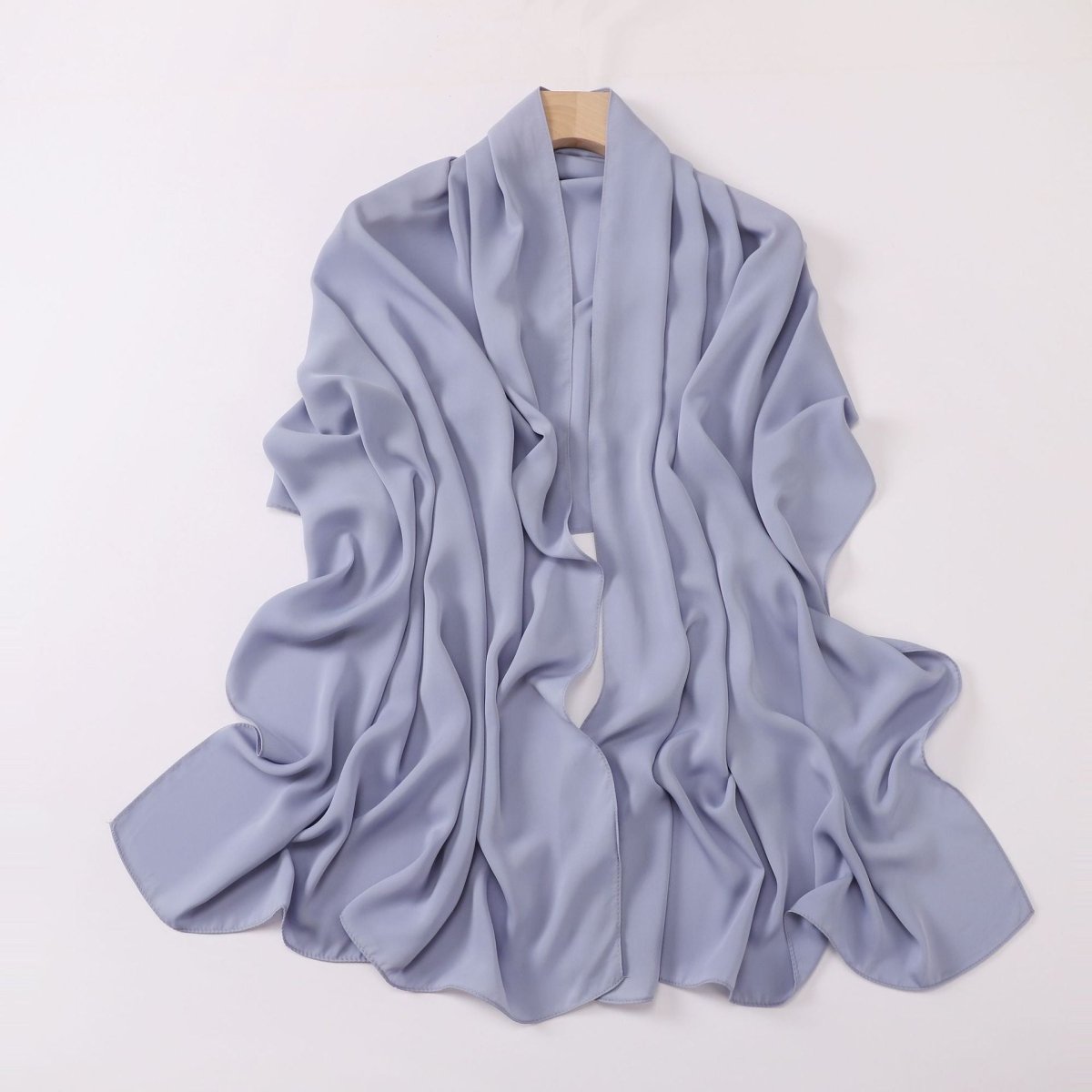 Light blue scarf on a wooden hanger against a white background