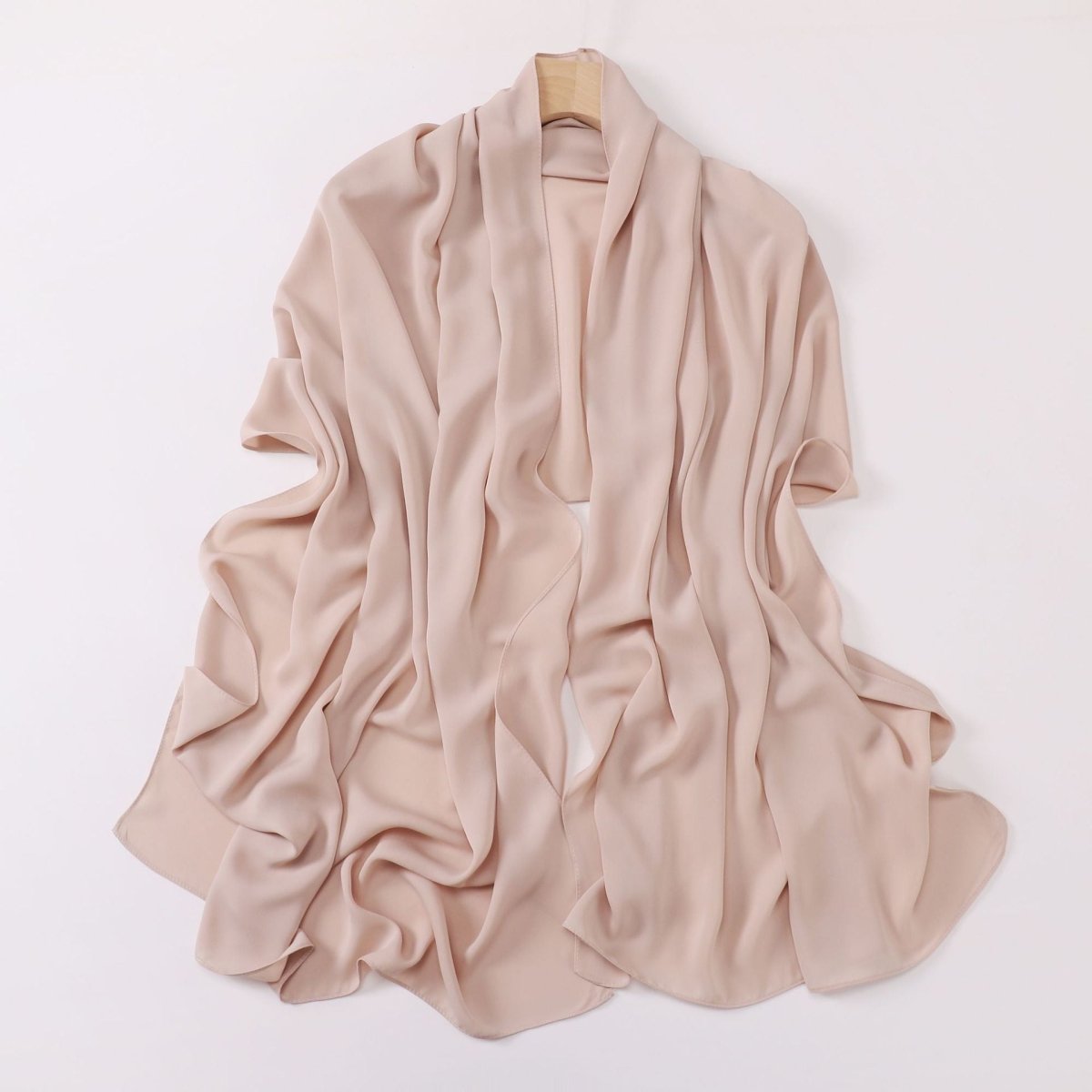 Beige scarf on a wooden hanger against a white background